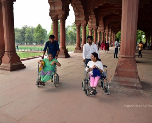 two volunteers helping two people on wheelchair in Delhi