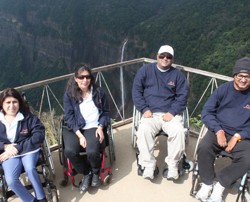 The team of four poses on a balcony with hills and waterfalls behind their back