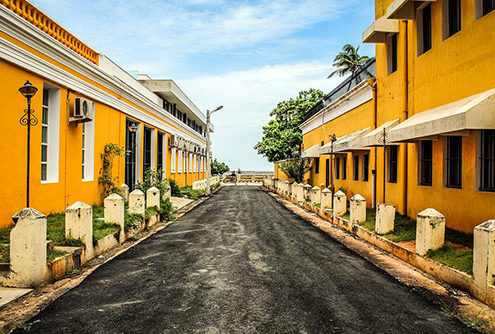 a street in puducherry with houses painted yellow and white on either sides leading upto the coast.