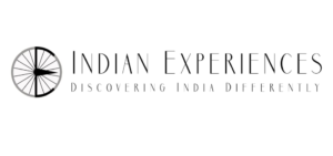 Indian Experiences Logo in black. A spoked wheel on the left and Text written in black in two lines. Discovering India Differently,