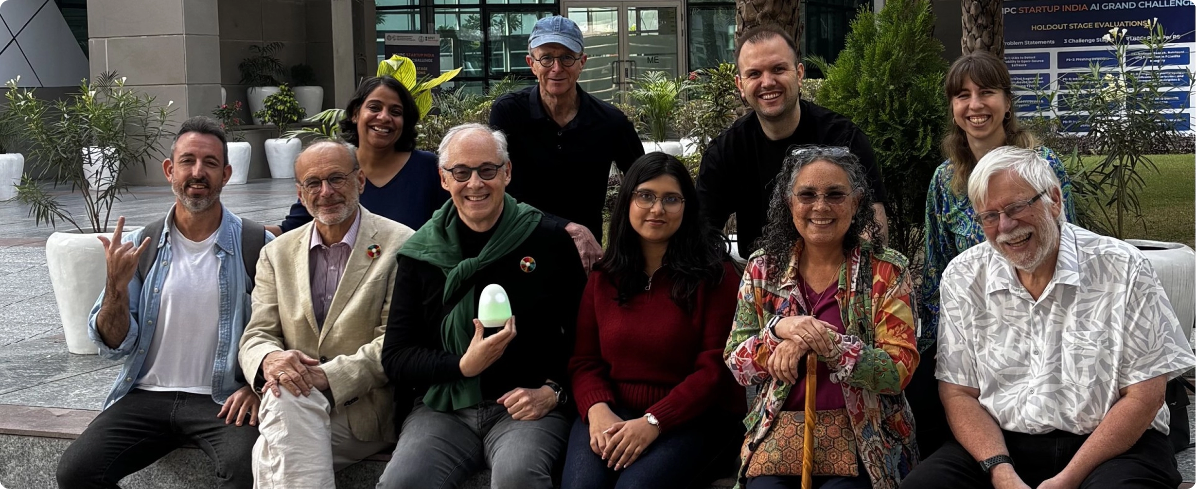 A diverse group of accessibility advocates and professionals posing together outdoors at an inclusive innovation or accessibility event.